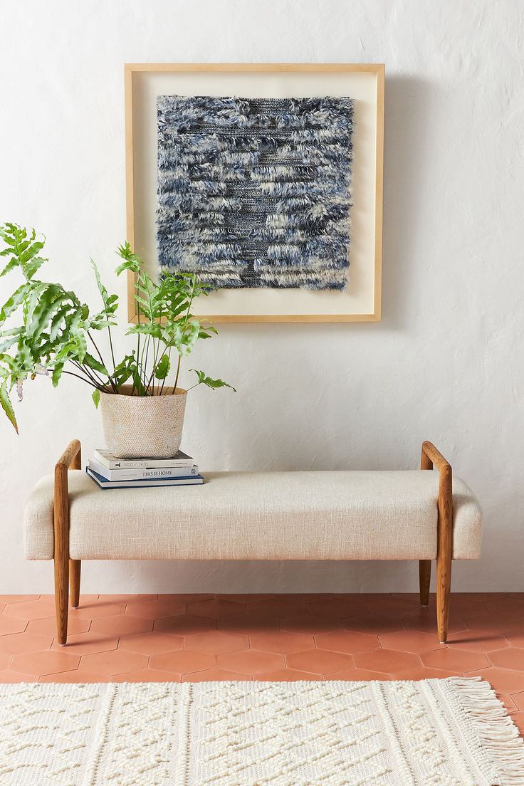 a potted plant sitting on top of a wooden bench next to a white rug