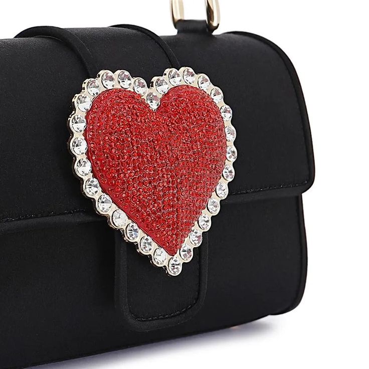 New this season, and one for the romantics, fall in love with the Amora Shoulder bag. Featuring a black leather outer with top handle, the newest design is adorned with a red crystal heart and outlined with clear crystal gems. Perfectly complement your date night fit or pick yours for the perfect gift for a loved one. Measurements: Width 18cm, Height 11.5cm, Depth 7cm Exterior: Textile, Leather, Interior: Textile, Leather HANDMADE IN: Spain Heart-shaped Black Shoulder Bag For Party, Luxury Bags For Valentine's Day, Valentine's Day Evening Bag With Detachable Strap, Luxury Shoulder Bag For Valentine's Day Evening, Luxury Heart-shaped Shoulder Bag With Detachable Strap, Luxury Evening Shoulder Bag For Valentine's Day, Luxury Heart-shaped Shoulder Bag For Gift, Luxury Heart-shaped Shoulder Bag As Gift, Luxury Valentine's Day Evening Shoulder Bag