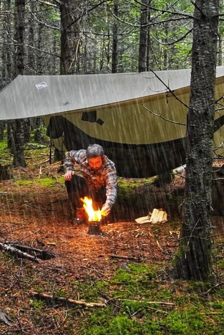 a man sitting in the woods next to a campfire with a boat on it