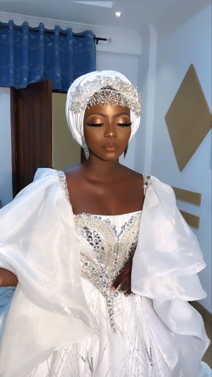 a mannequin dressed in a white dress and headdress is standing next to a bed