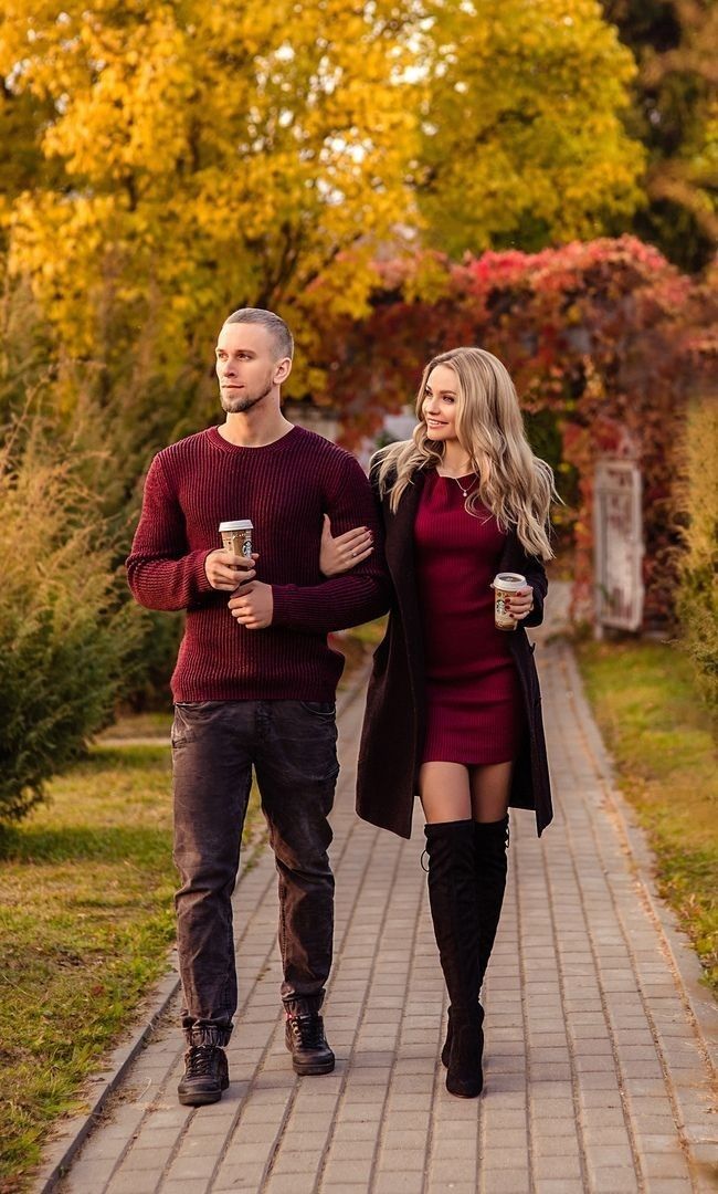 a man and woman walking down a sidewalk with coffee in their hands, both wearing boots