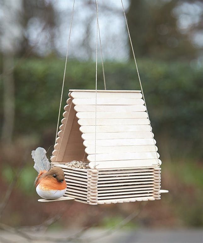 a small bird is perched on a hanging bird feeder that has been made out of wood