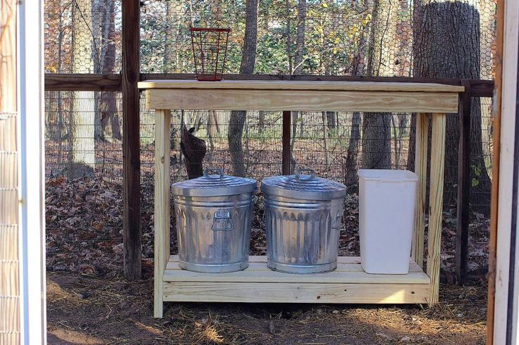 two metal buckets sitting on top of a wooden shelf in front of a fence