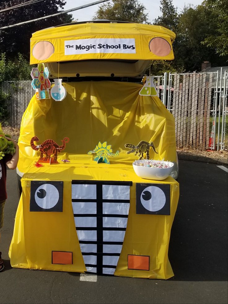 a child standing in front of a yellow school bus with decorations on it's side