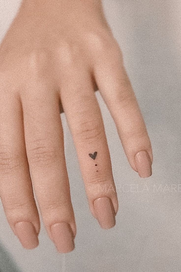 a woman's hand with a tiny heart tattoo on her left thumb and finger