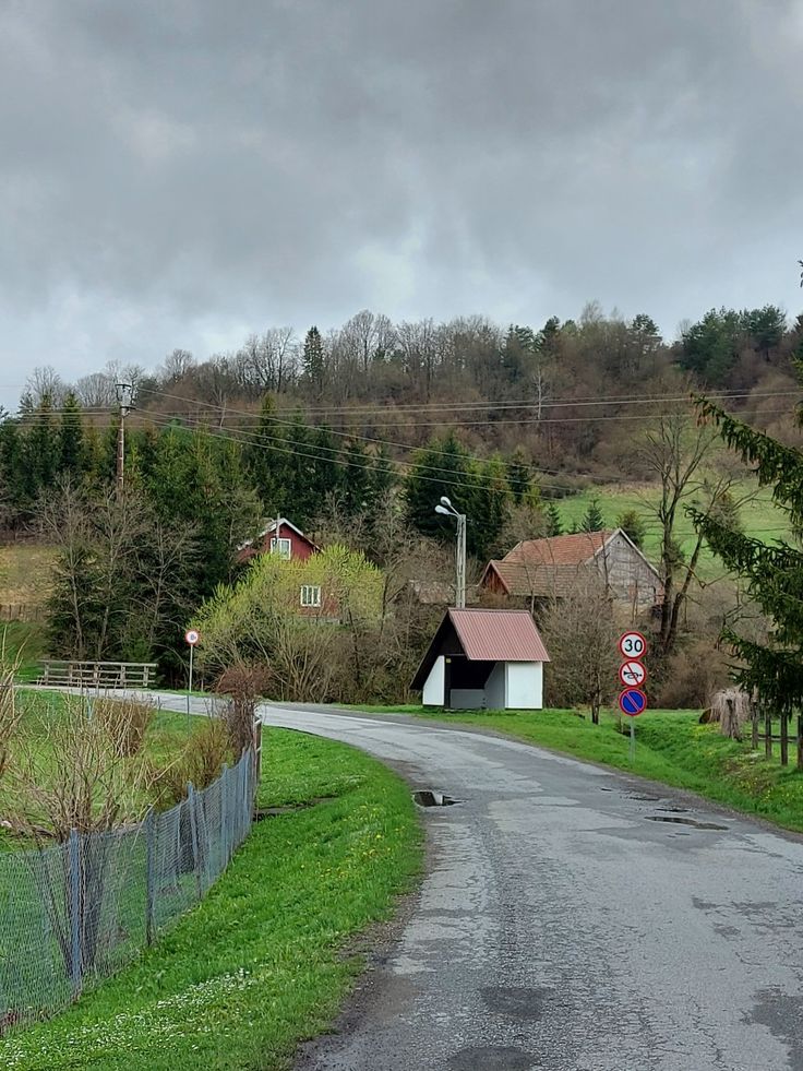 an empty country road in the middle of a rural area with houses on either side