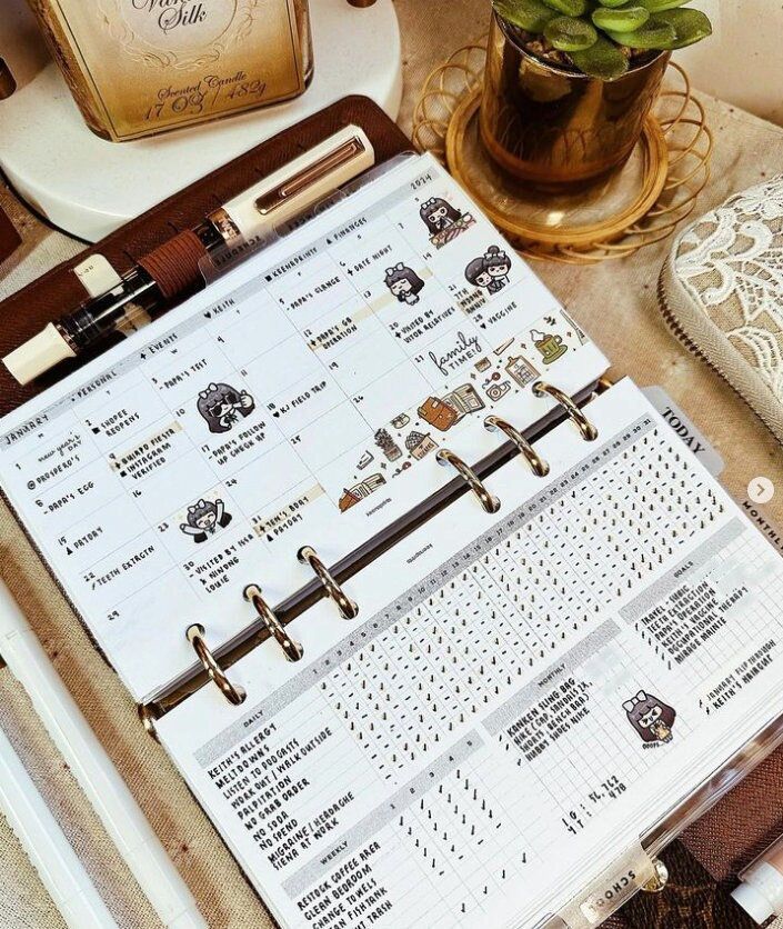 an open planner sitting on top of a table next to a potted plant and other items