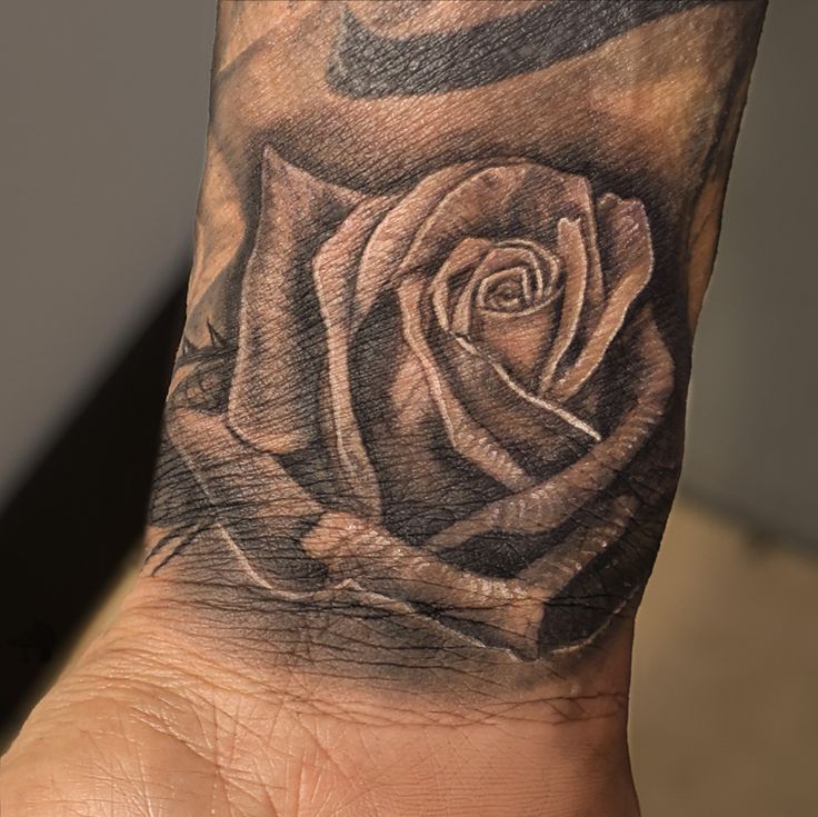 a hand with a rose tattoo on it