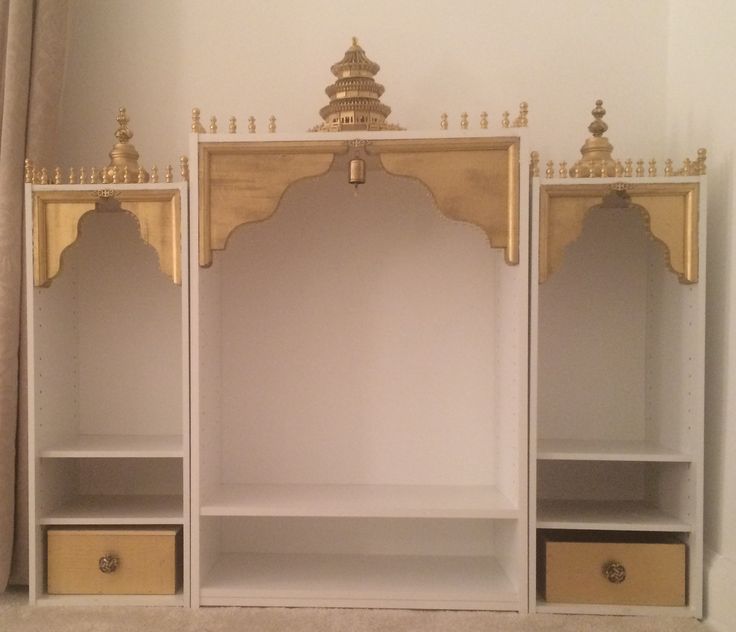 a white shelf with two yellow drawers and gold trimmings on the top, in front of a beige curtained window