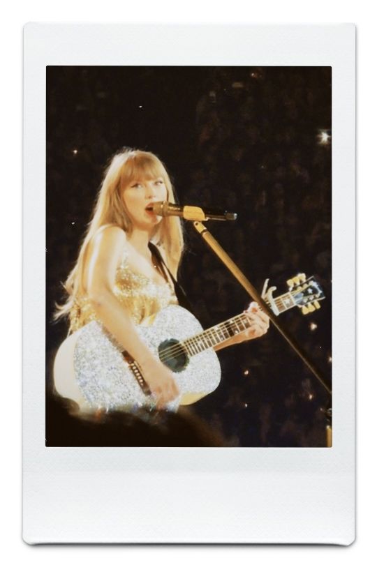 a woman with blonde hair playing guitar in front of a microphone and audience at a concert