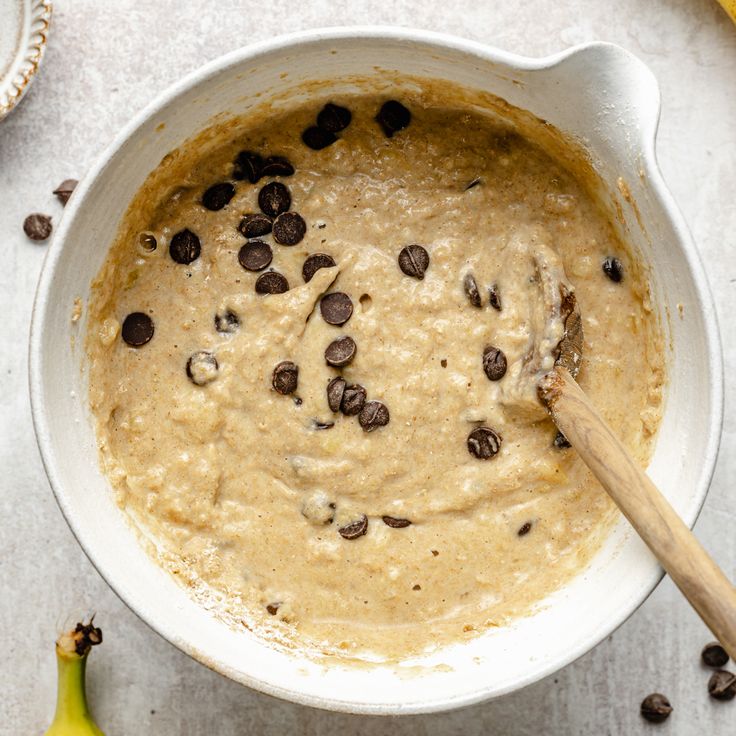 a bowl filled with oatmeal and chocolate chips next to two banana's