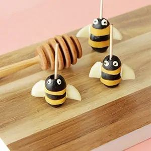 three bees are sitting on top of a cutting board with sticks sticking out of them