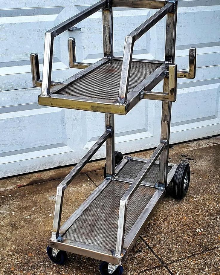 a metal and wood cart sitting in front of a garage door with wheels on it