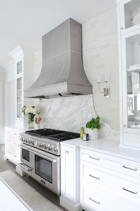 a stove top oven sitting inside of a kitchen next to white cupboards and drawers