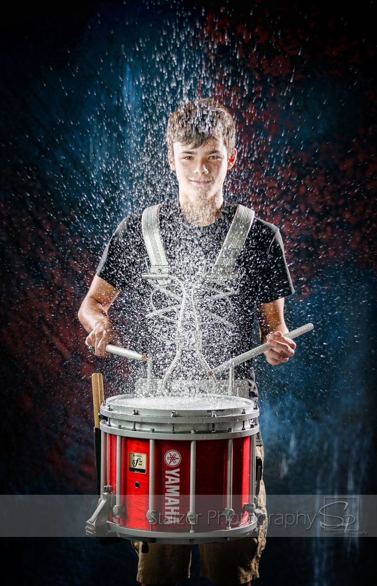 a man holding a drum and splashing water on it with his hands in front of him