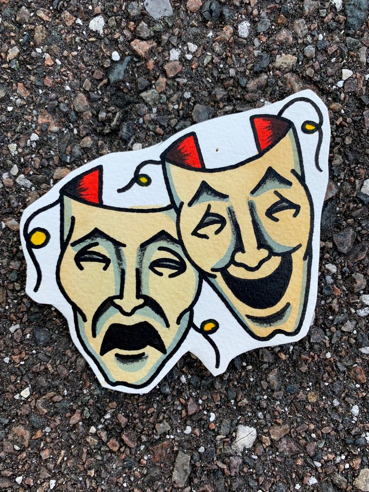 a sticker with two faces on it sitting on the ground next to some rocks