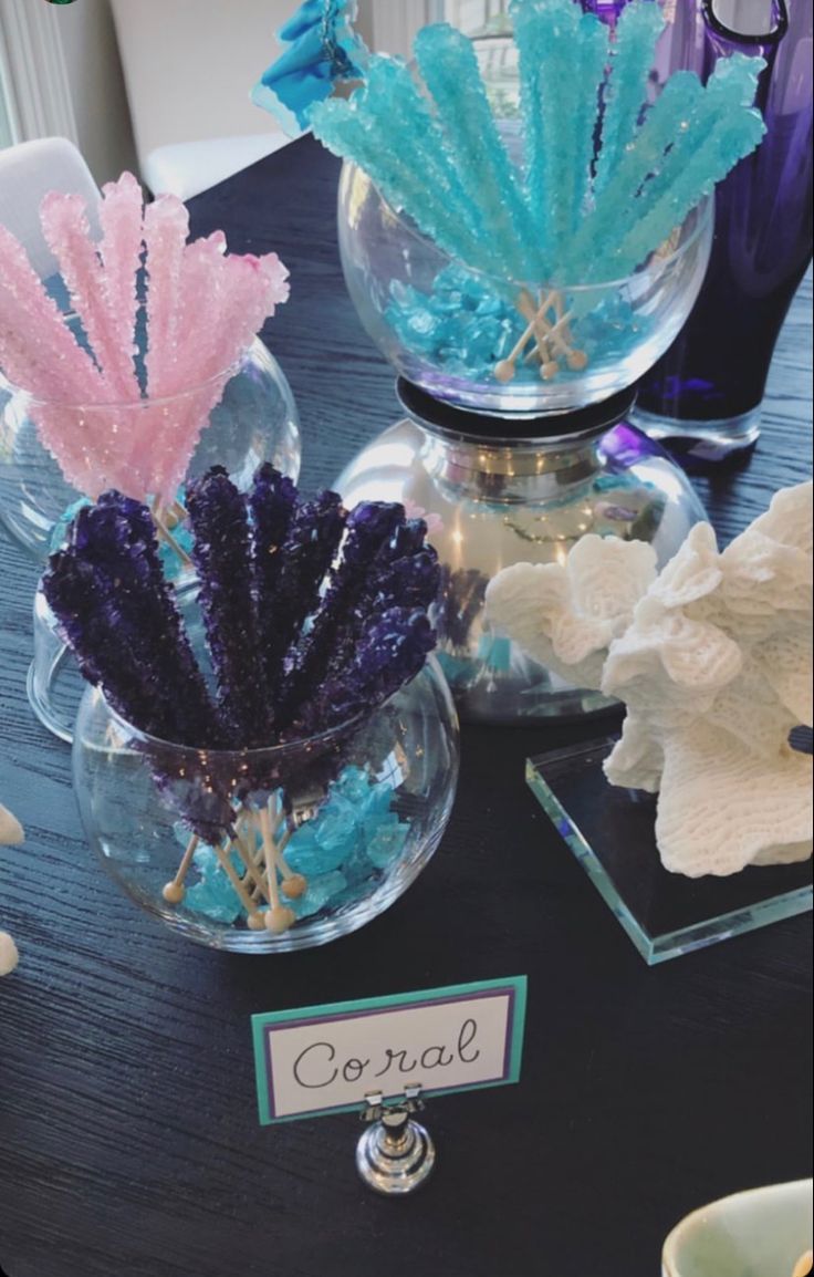 two vases filled with different colored seaweed on top of a wooden table next to each other