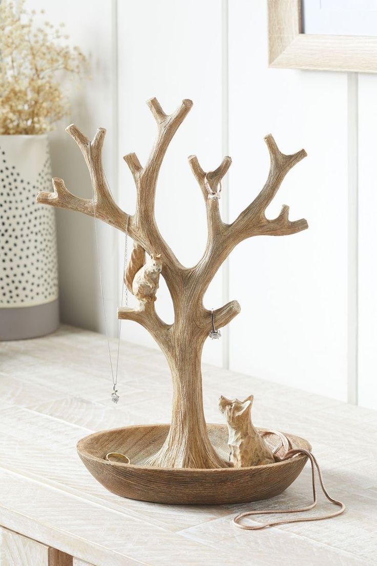 a wooden tree with animals in it on a table next to a potted plant