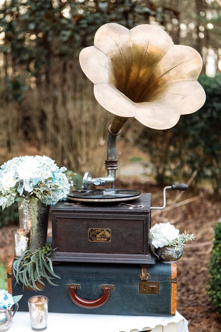 an old record player on top of two suitcases with flowers in the middle and other decorations around it