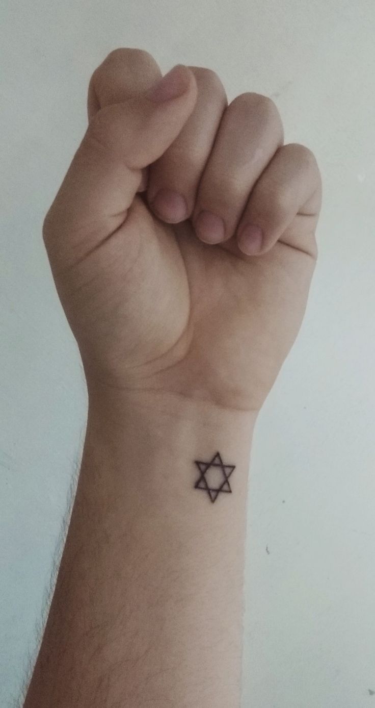 a hand with a small star tattoo on it's left wrist, holding up the fist