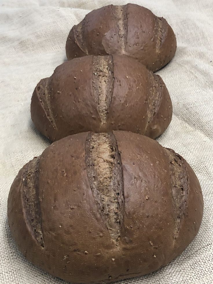 three loaves of bread sitting on top of a white cloth