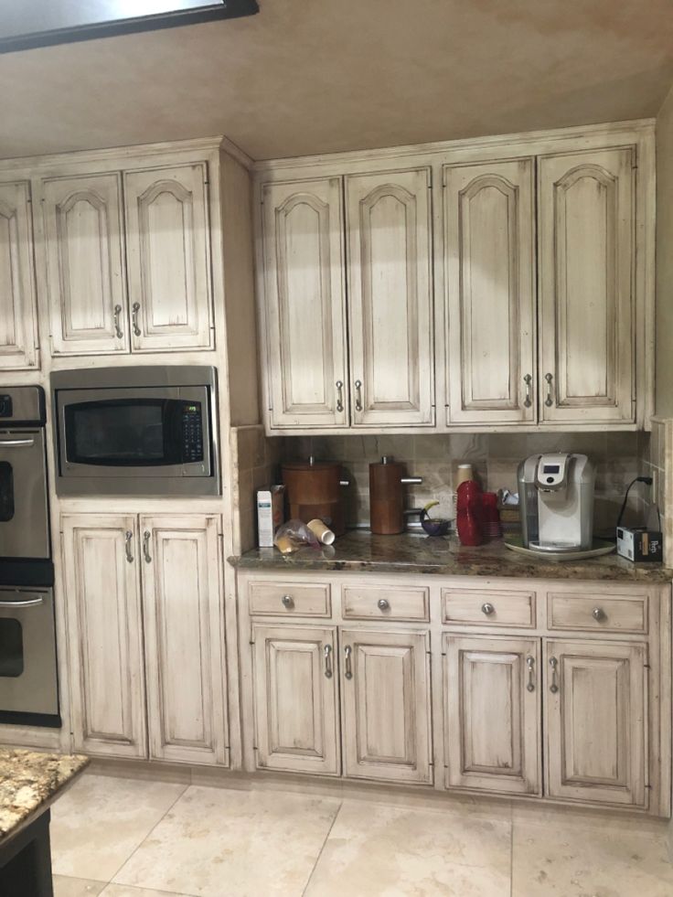 a kitchen with white cabinets and stainless steel appliances in the center, along with marble counter tops