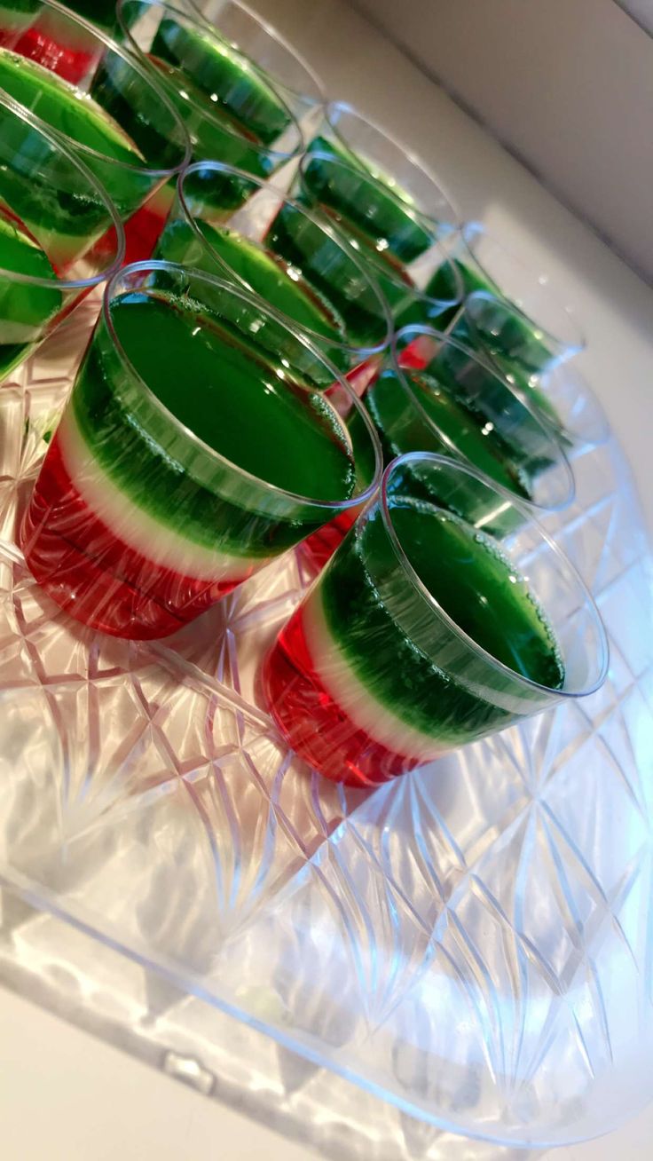 there are many glasses that have watermelon slices in them on the trays