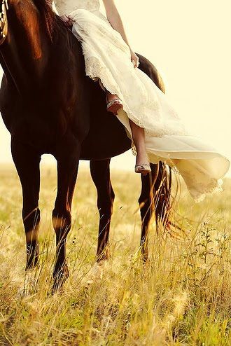 a woman riding on the back of a brown horse in a field with tall grass