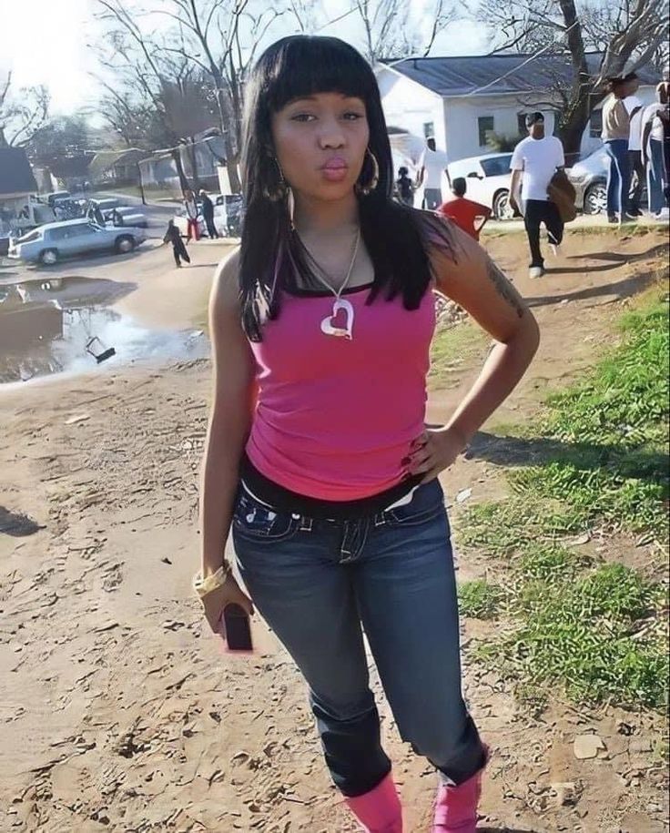 a woman in pink shirt and jeans standing on dirt