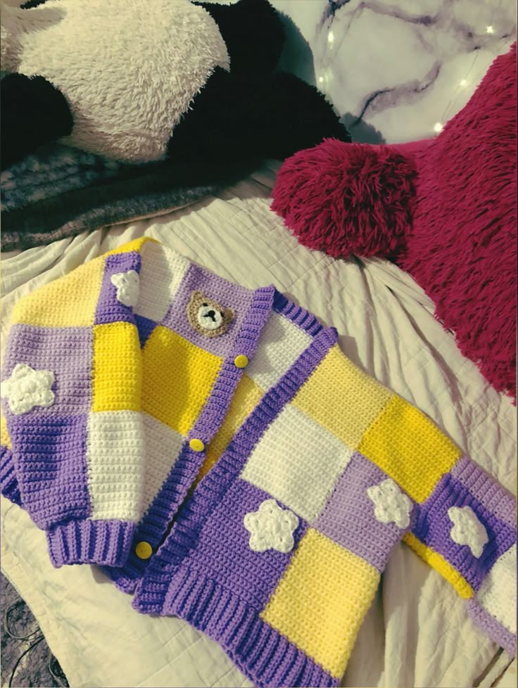 there is a knitted sweater and teddy bear on the bed