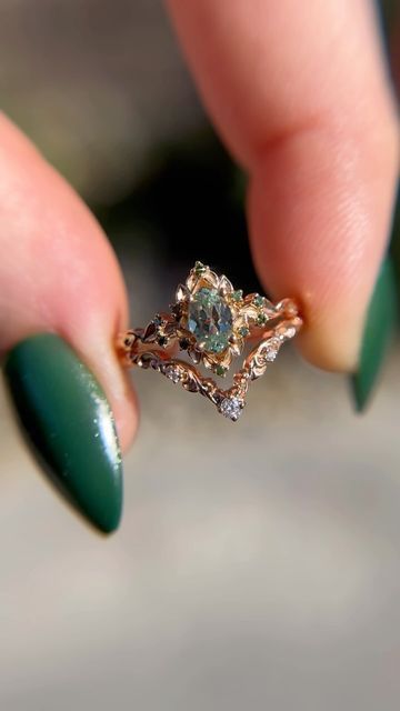 a woman's hand holding a ring with green fingernails