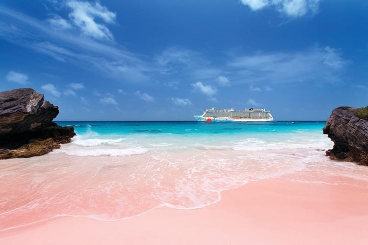 a cruise ship is in the distance as it sits on an ocean beach with pink sand