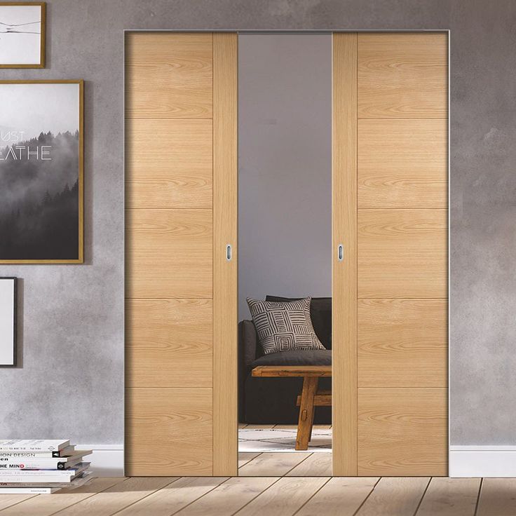 an open wooden door in a living room next to a chair and table with pictures on the wall