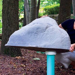 a man kneeling down next to a large rock