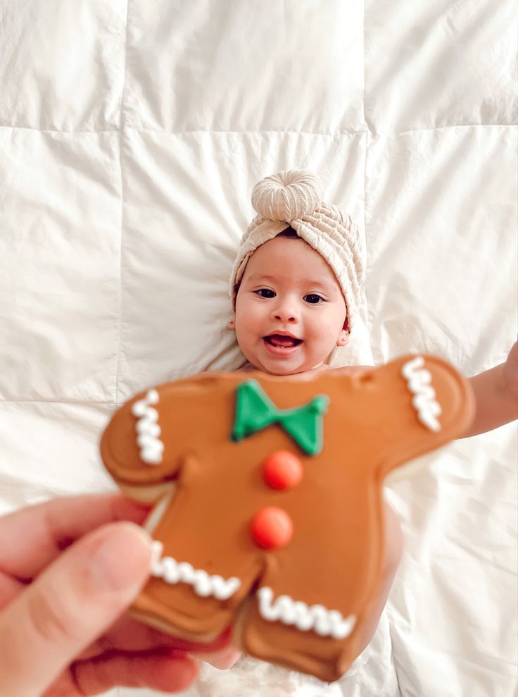 a baby is holding a ginger shaped cookie