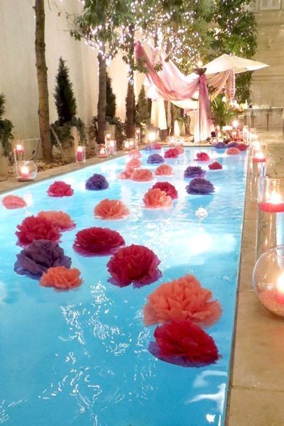 an outdoor pool decorated with flowers and candles