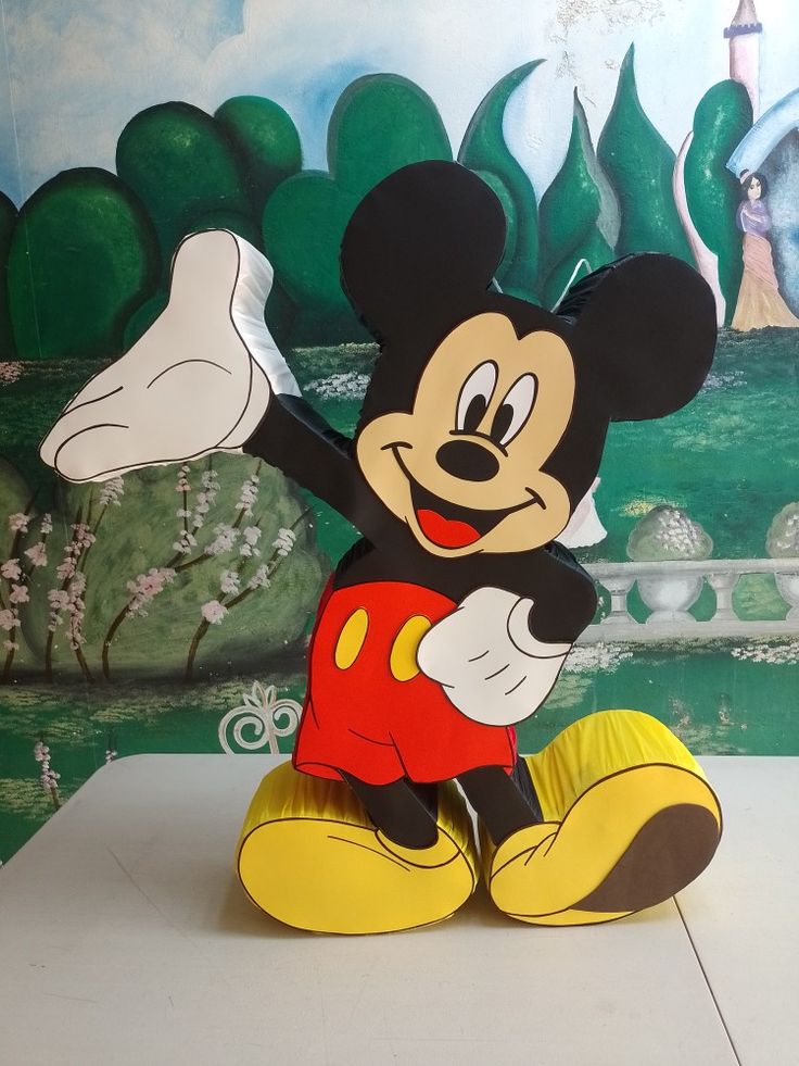 a mickey mouse statue sitting on top of a white table in front of a painting