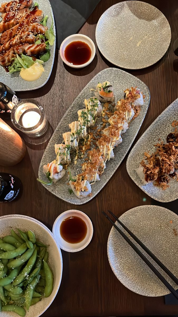 a table topped with plates and bowls filled with different types of food next to dipping sauces