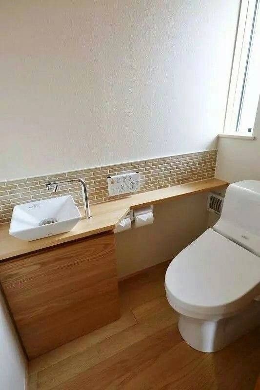 a white toilet sitting next to a sink in a bathroom on top of a hard wood floor