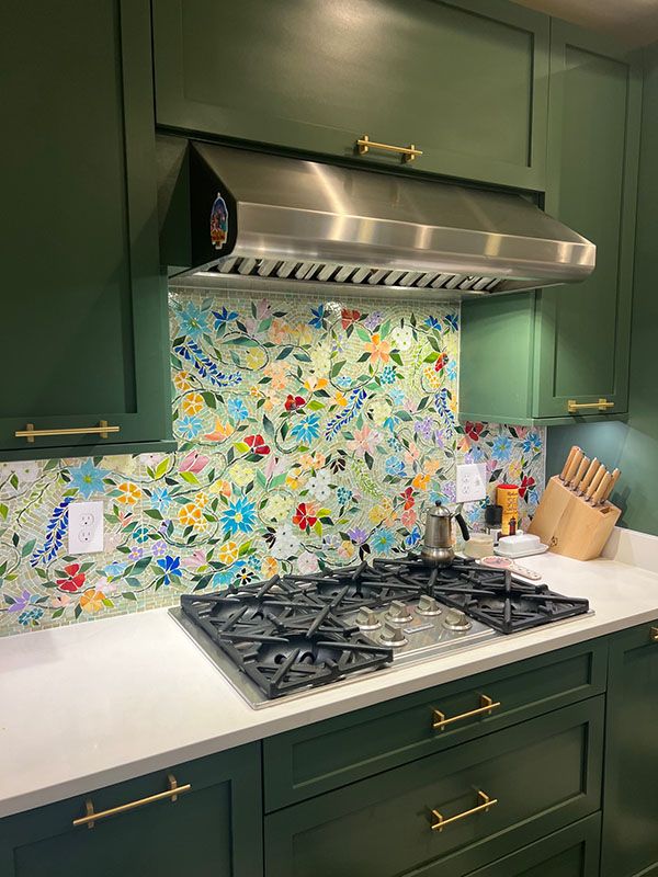 a stove top oven sitting inside of a kitchen next to green cabinets and counter tops