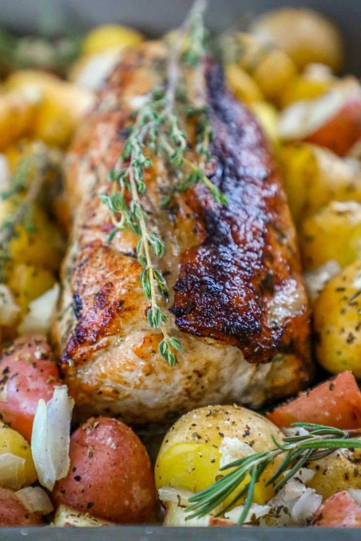 chicken, potatoes and carrots in a pan with rosemary sprig on top