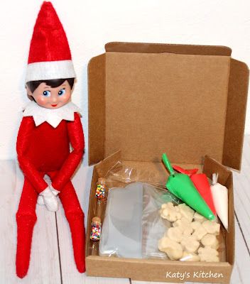 an elf is sitting next to a box of treats