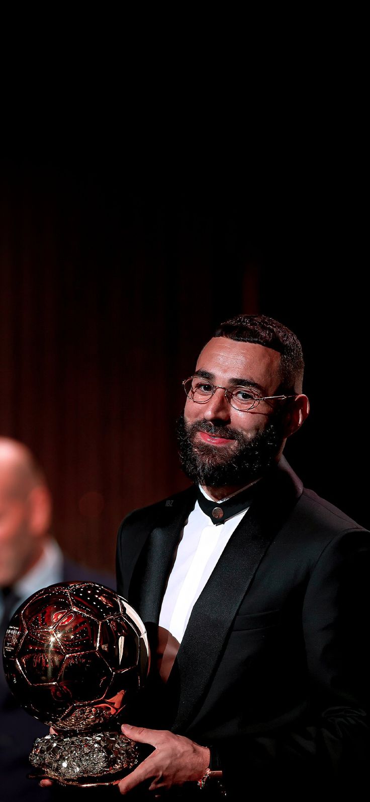 a man in a tuxedo holding a soccer ball