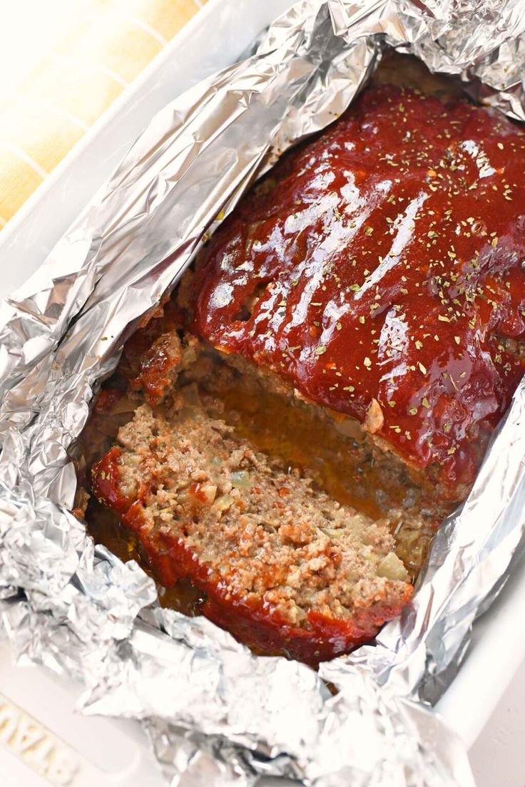 meatloaf in foil with sauce and seasoning on top