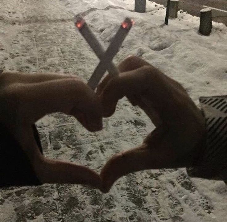 someone making a heart with their hands in the snow