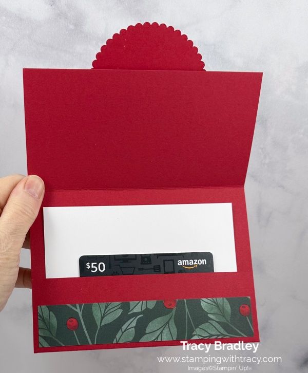 someone holding up a red card with the amazon logo on it and an envelope that says $ 50