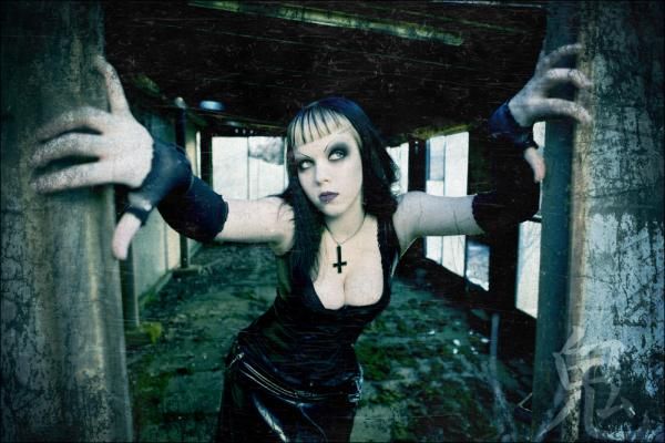 a woman dressed in black posing for a photo with her hands on the railings