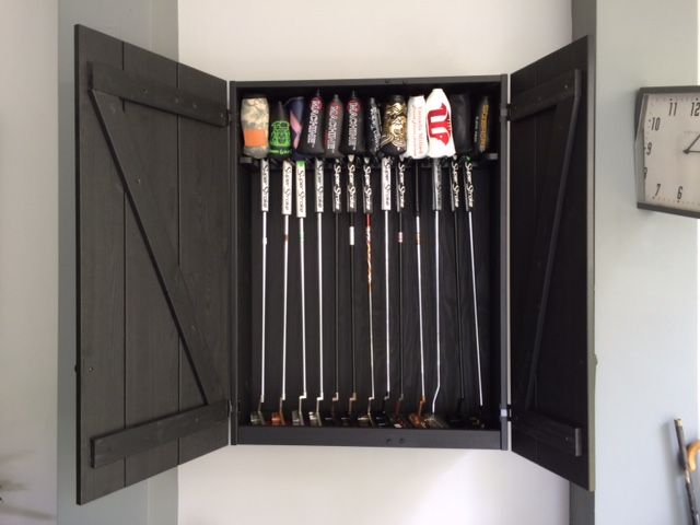 an open cabinet with golf clubs in it and a clock on the wall behind it