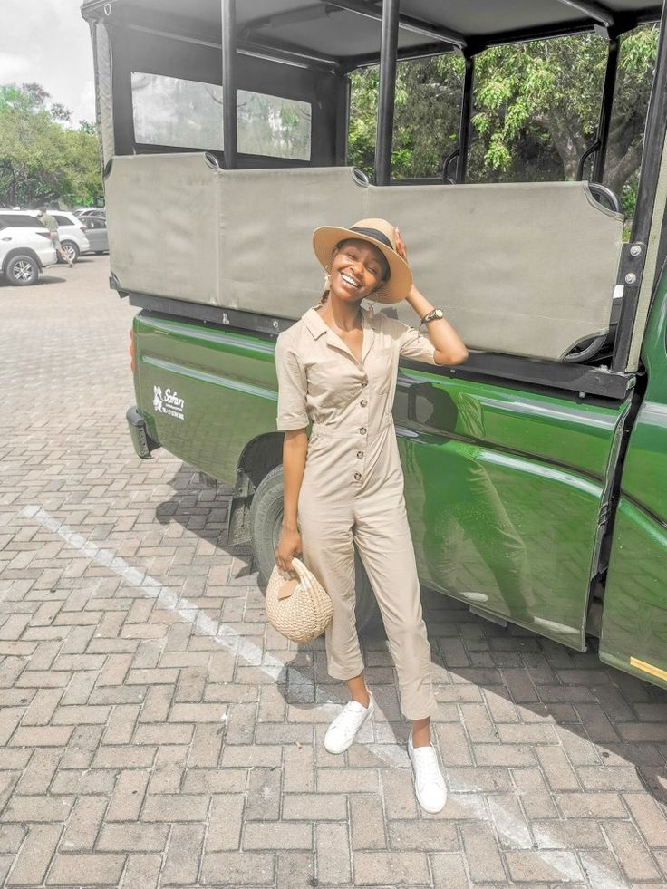 a woman standing in front of a green bus with her hand on her head and smiling