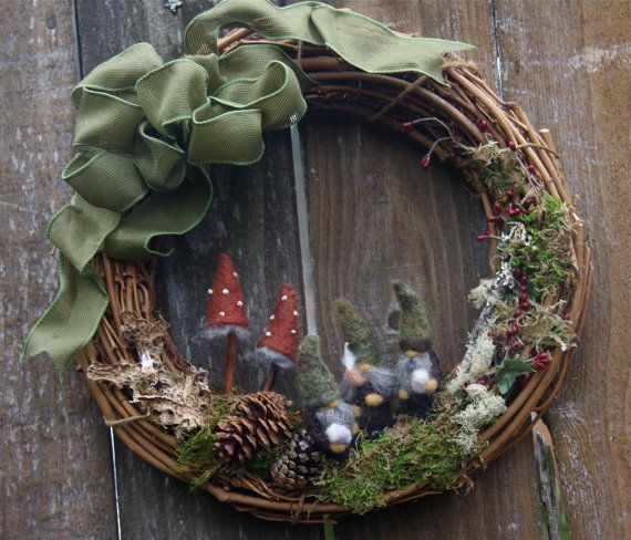 a wreath with gnomes and pine cones is hanging on a wooden door frame,